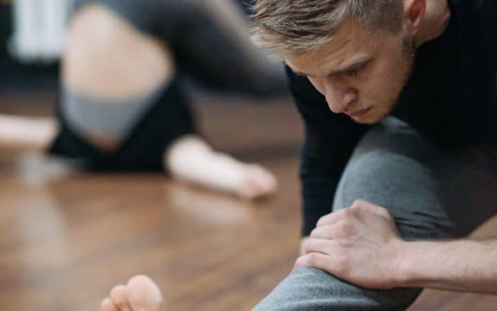 A man stretches in a gym setting, focusing on flexibility and fitness.